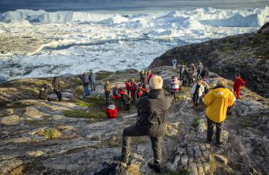 Visitors overlook the Ilulissat Icefjord from Sermermiut 